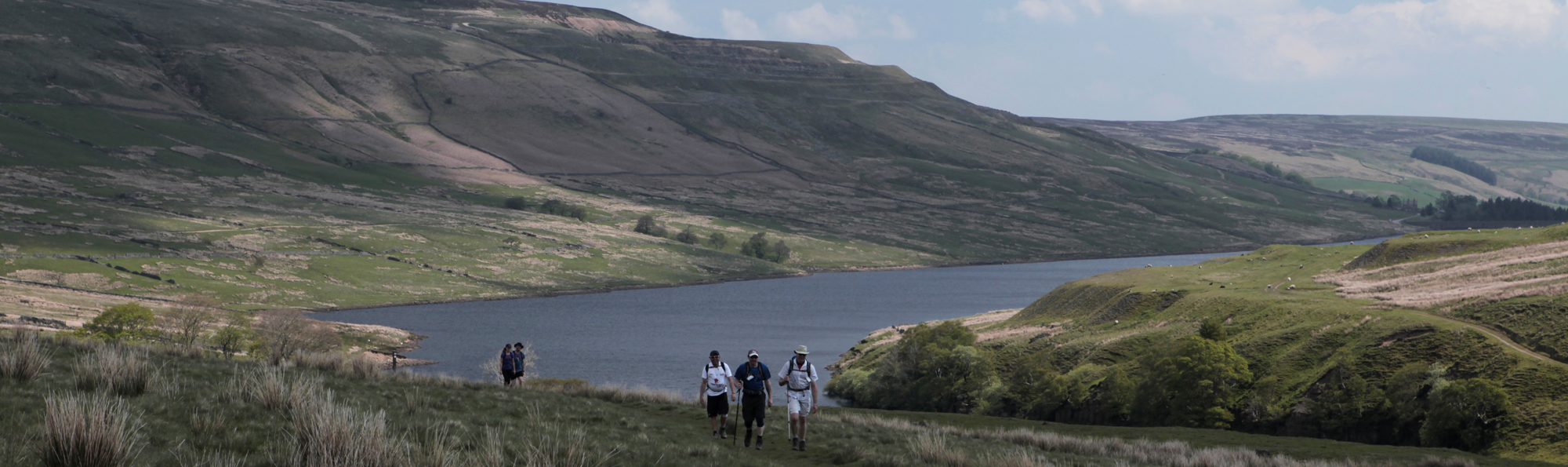 People walking in the countryside with reservoir behind them