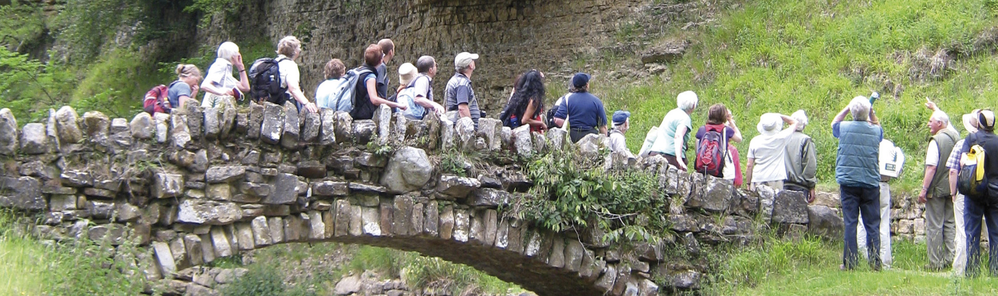 A large group of people stood on an old stone bridge