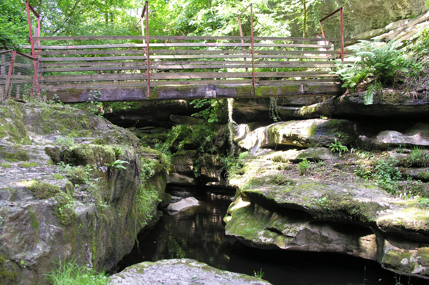 A wooden bridge across a gorge with large jagged rock formations at both sides