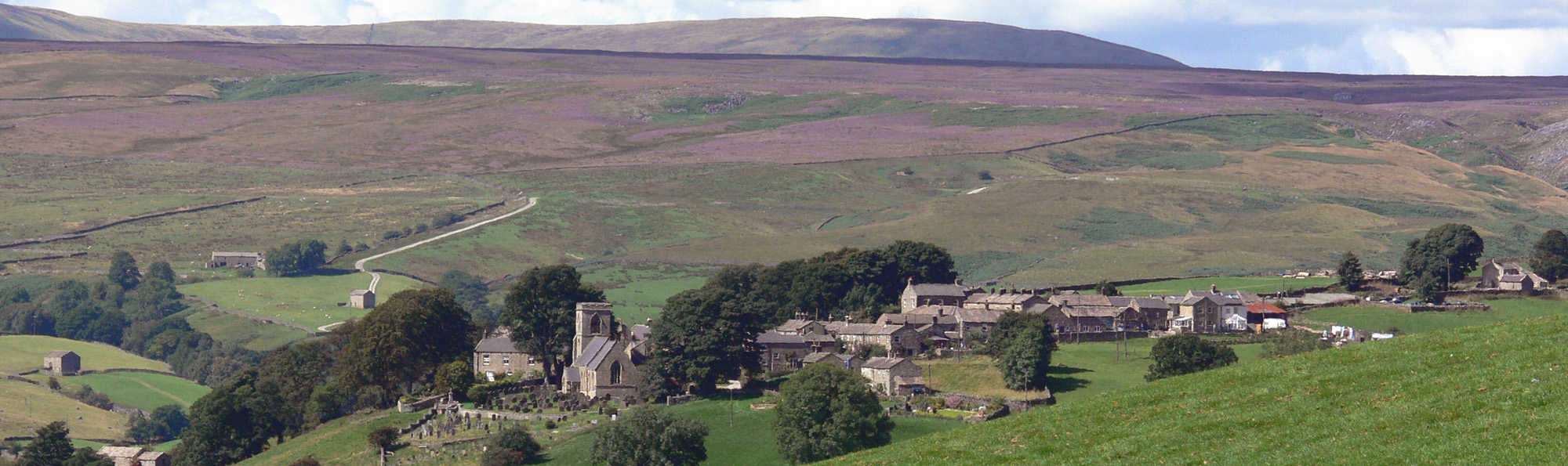 Middlesmoor village taken from above with purple heather moorland in the background