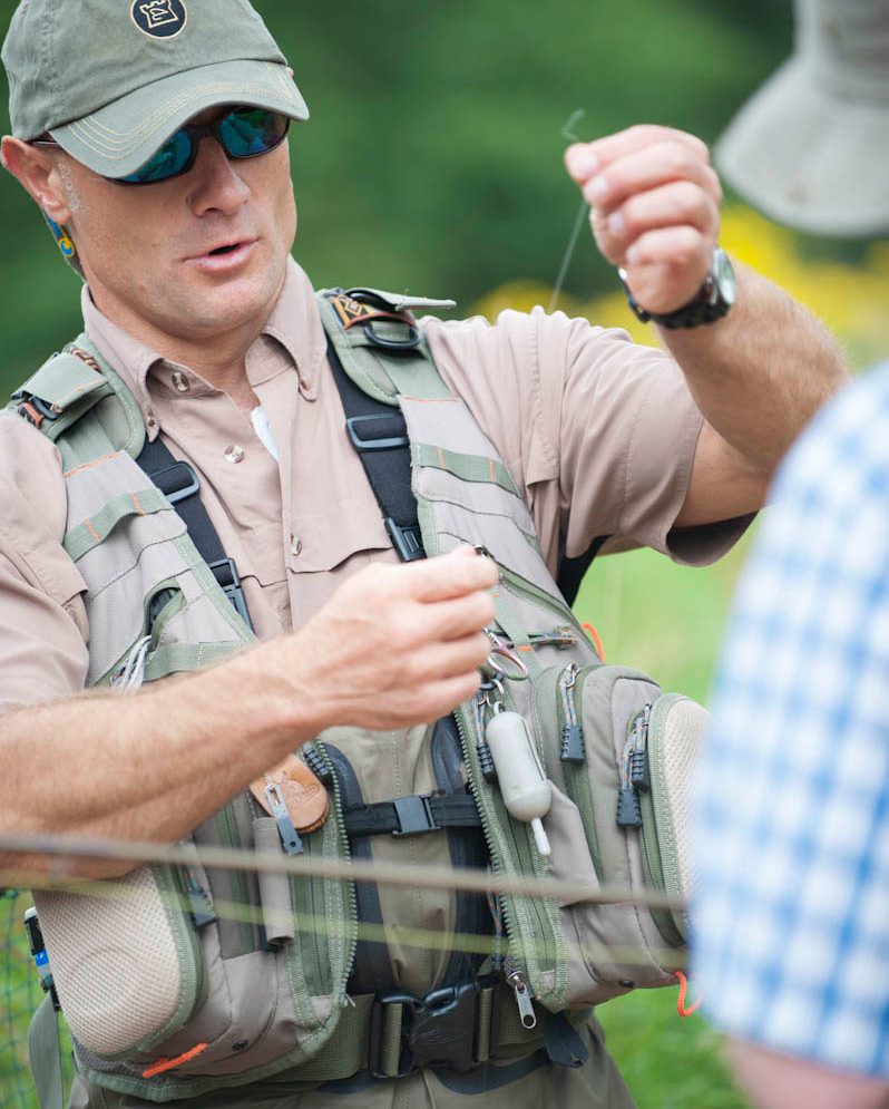 A close up of a fisherman wearing a cap and sunglasses holding a piece of string with both hands
