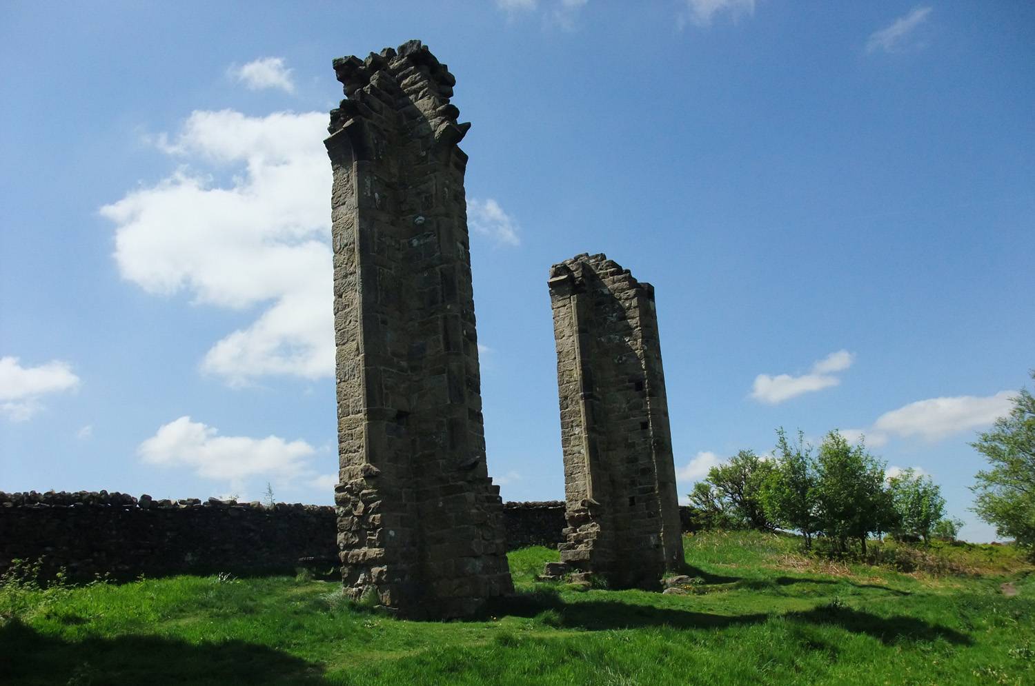 The two towers of Yorke's Folly with a dry stone wall behind them
